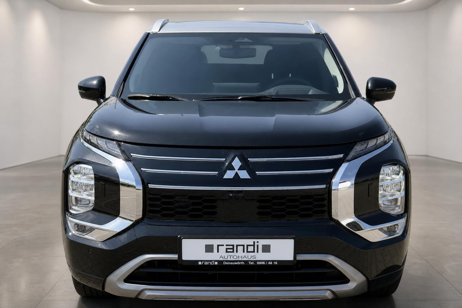 Mitsubishi Outlander PHEV schwarz direkte Frontansicht mit Chromgrill im Showroom