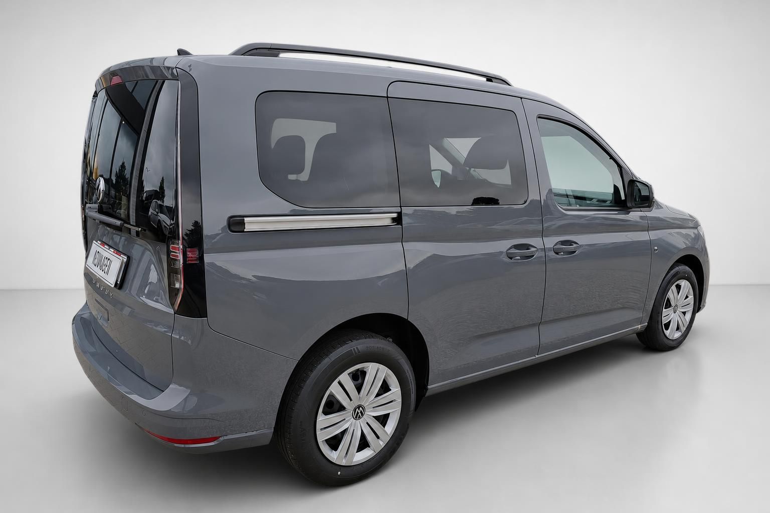 VW Caddy in Grau, Heckansicht schraeg von hinten