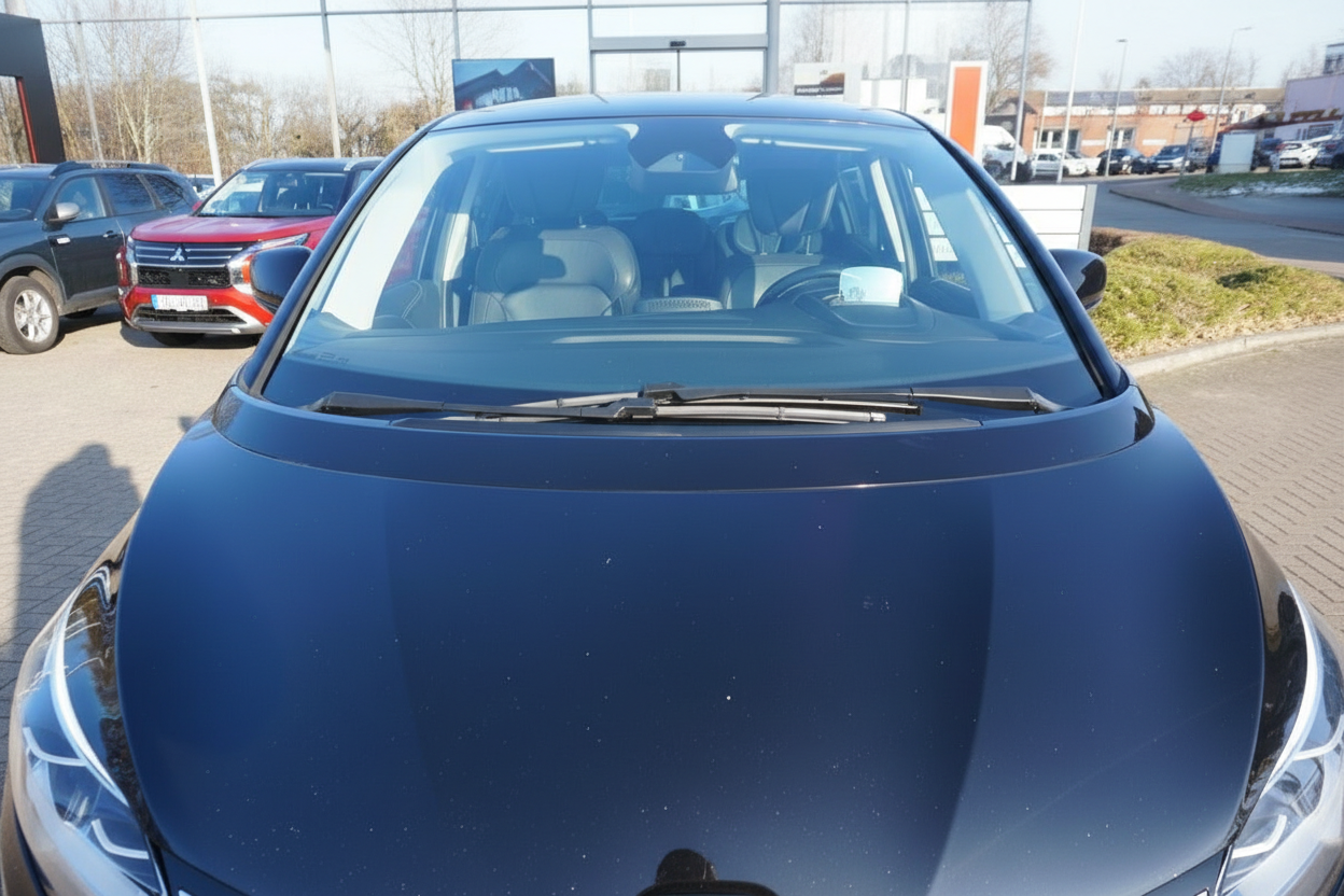 Blauer Tesla Model 3 Frontansicht mit Motorhaube und Windschutzscheibe auf Händlerparkplatz