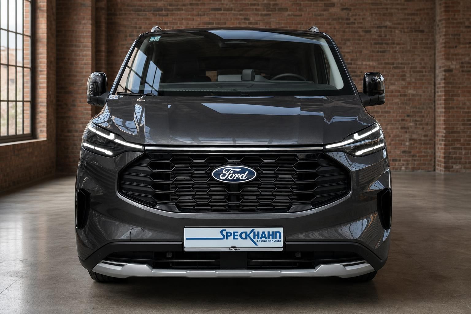 Ford Tourneo Custom grau Frontansicht mit Ford-Logo und Speckhahn Händlerkennzeichen im Studio