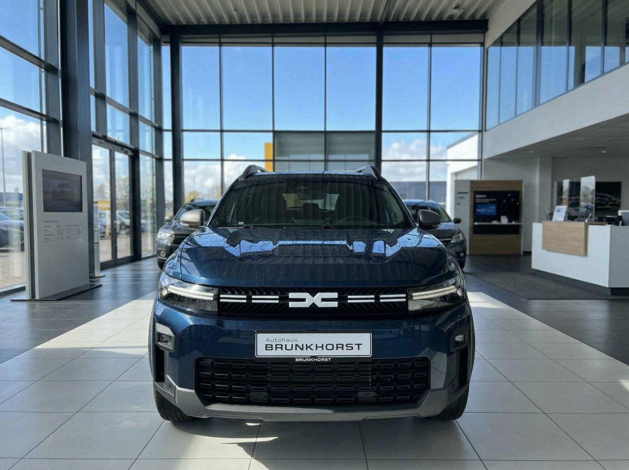 Frontansicht eines blauen Dacia SUV mit modernem Design im Autohaus-Showroom