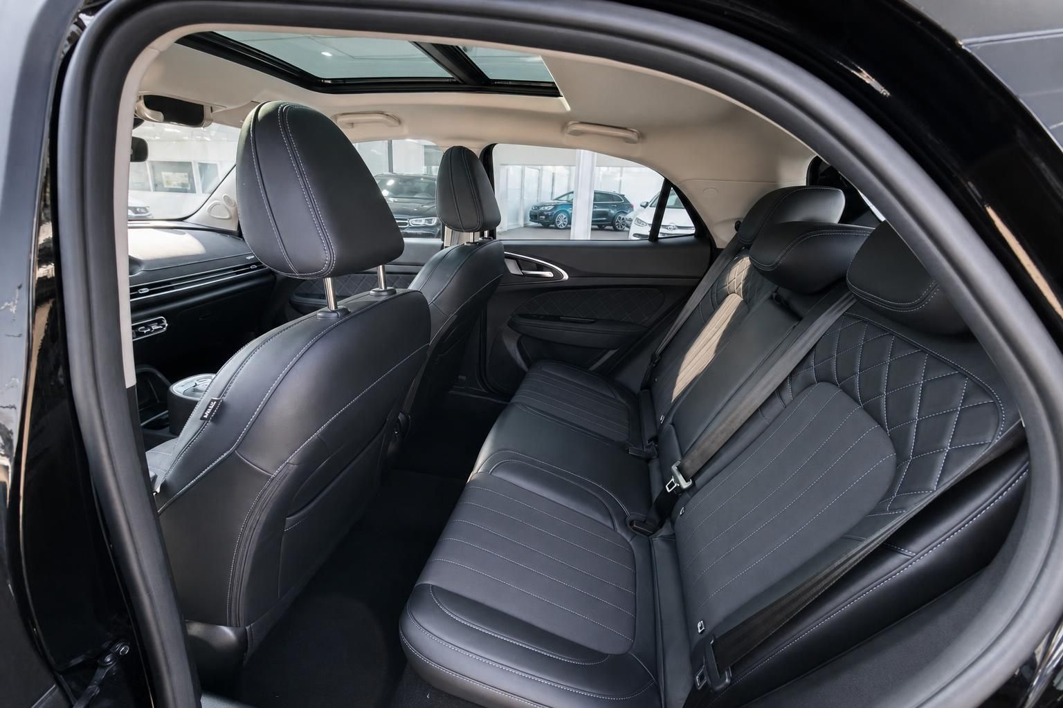 Rücksitze schwarzes Fahrzeug mit gesteppten Bezügen und Sicherheitsgurten im Showroom