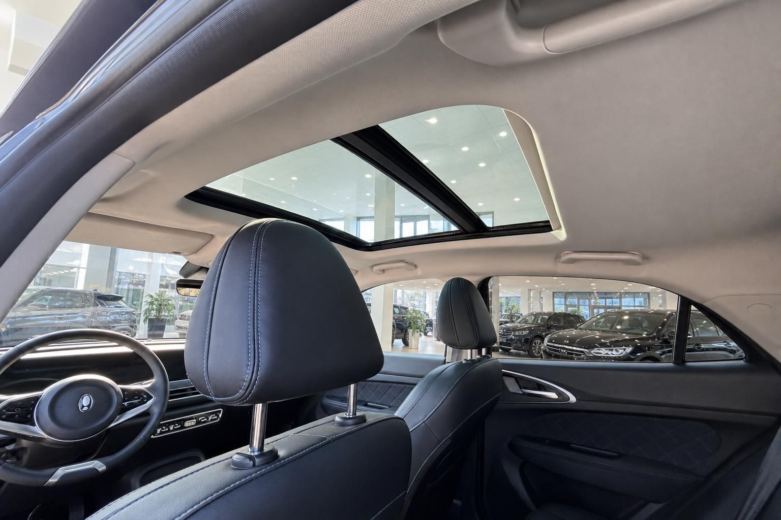 Innenraum eines Fahrzeugs mit schwarzem Leder, Panorama-Schiebedach und modernem Cockpit-Design