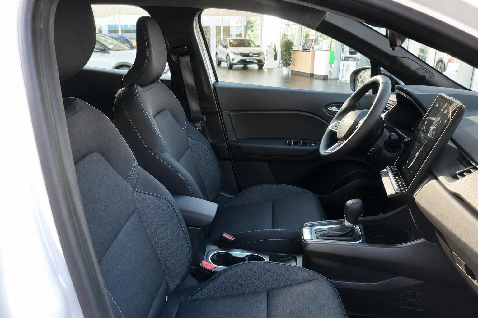 Fahrzeuginnenraum mit dunklen Sitzen, Mittelkonsole und modernem Dashboard-Design