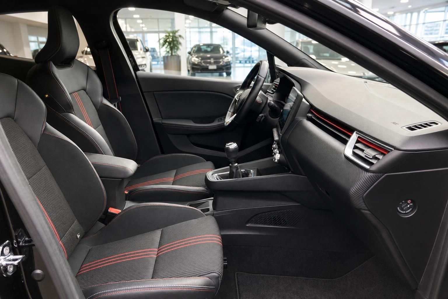 Fahrzeuginnenraum mit schwarzen Sportsitzen mit roten Ziernähten, Mittelkonsole und Infotainment-Display