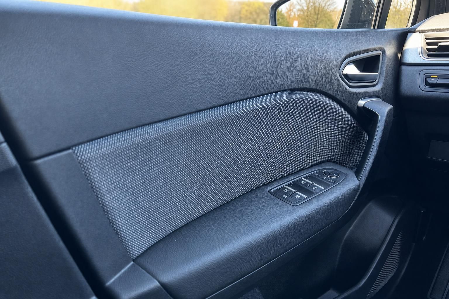 Detailaufnahme der vorderen Türverkleidung mit Fensterheber-Bedienung und Stoffbezug