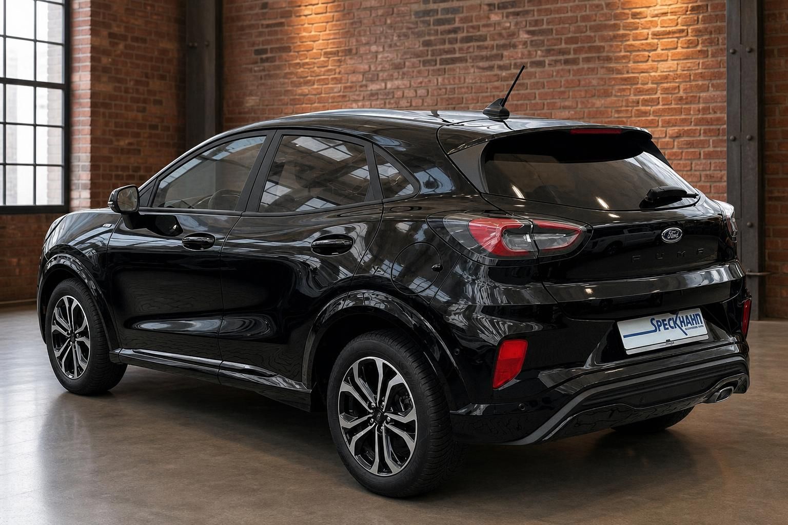 Ford Puma schwarz Heckansicht schräg links mit Spoiler und Leichtmetallfelgen im Showroom