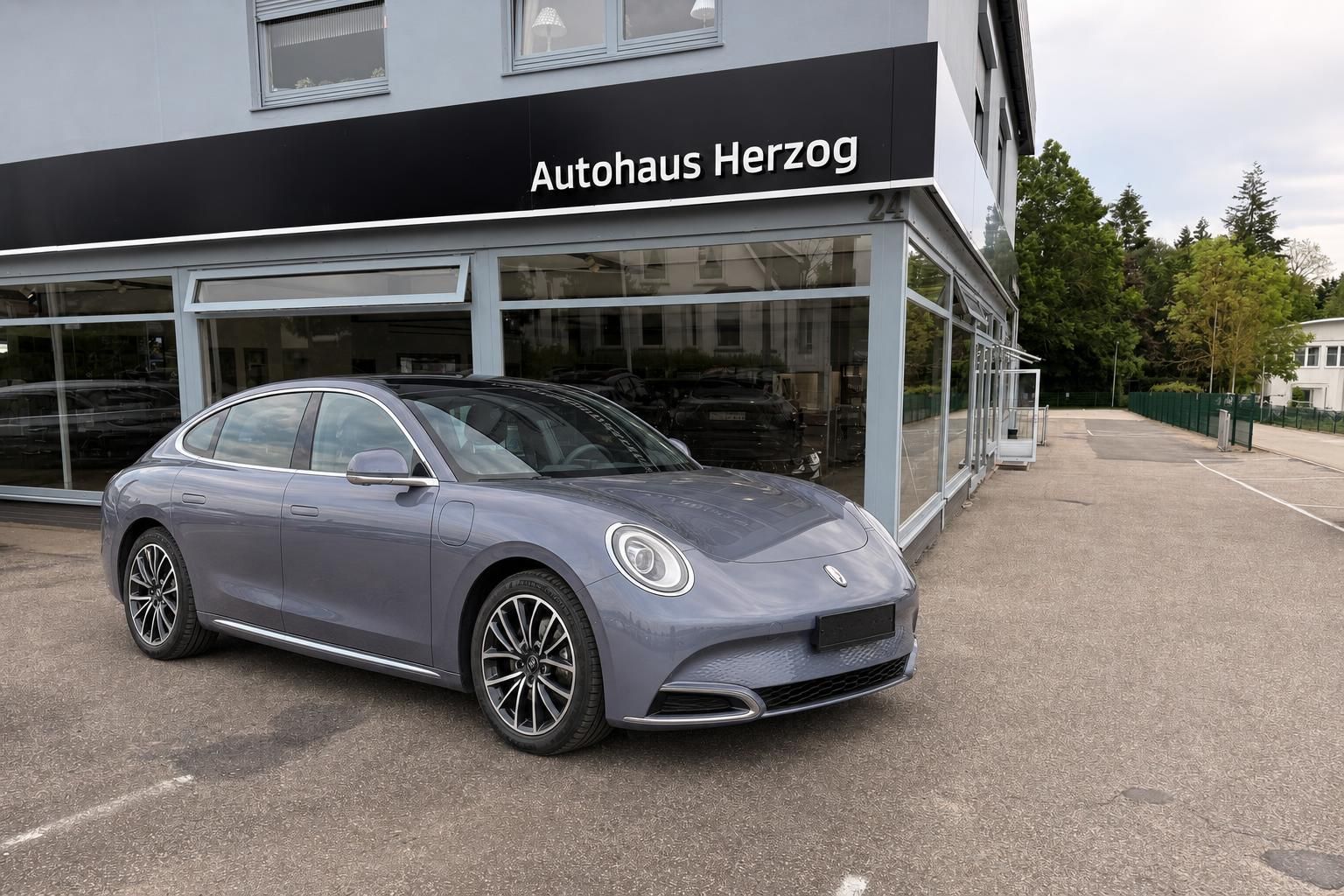 Grauer Elektro-Sportwagen vor Autohaus Herzog - Seitenansicht mit eleganten Felgen