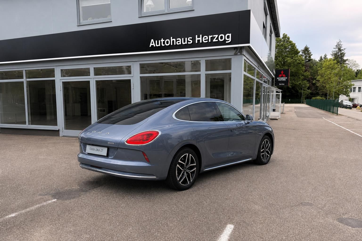 ORA Elektroauto grau Heck-Seitenansicht links - sportliche Elektro-Limousine vor Autohaus Herzog