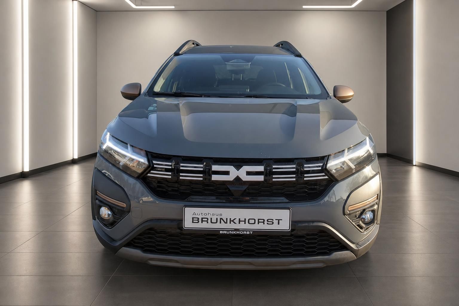 Dacia SUV Frontansicht in Grau mit LED-Scheinwerfern im Showroom