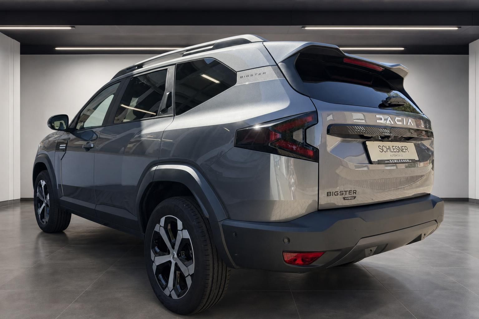 Dacia Bigster Hybrid grau Heckansicht mit Dachreling im Showroom