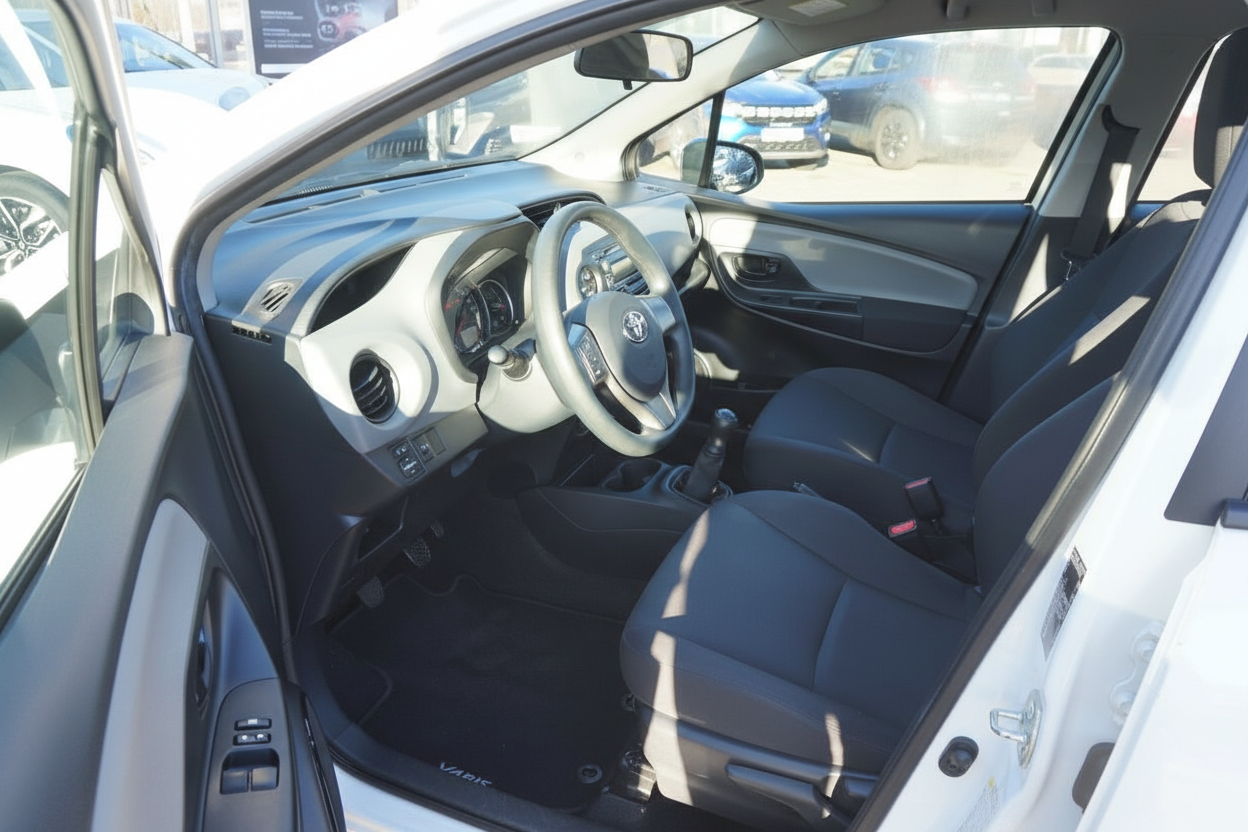 Toyota Yaris Innenraum mit schwarzen Stoffsitzen, Lenkrad und Schaltgetriebe – Fahrerseite geöffnet