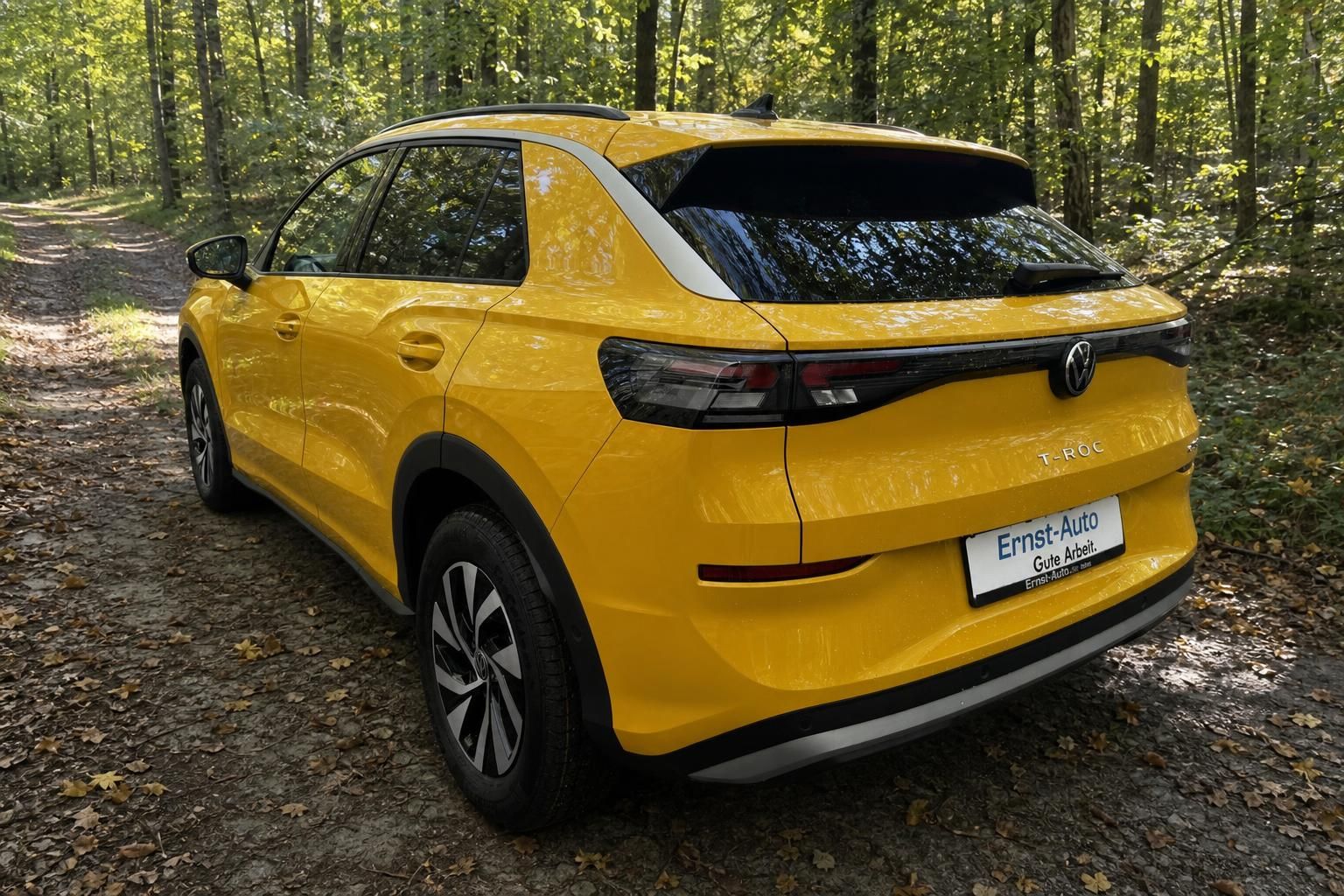 Gelber Volkswagen T-Roc SUV Heckansicht mit Händlerkennzeichen Ernst-Auto im Wald