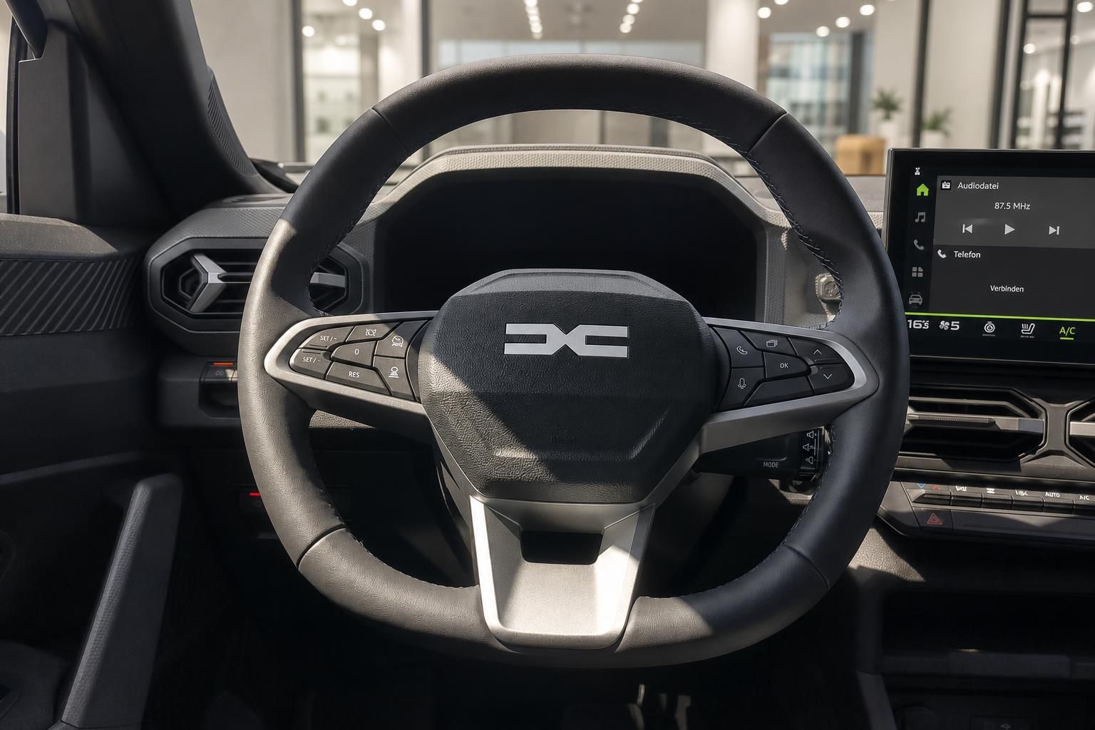 Dacia Lenkrad mit Multifunktionstasten und Infotainment-Display im Hintergrund