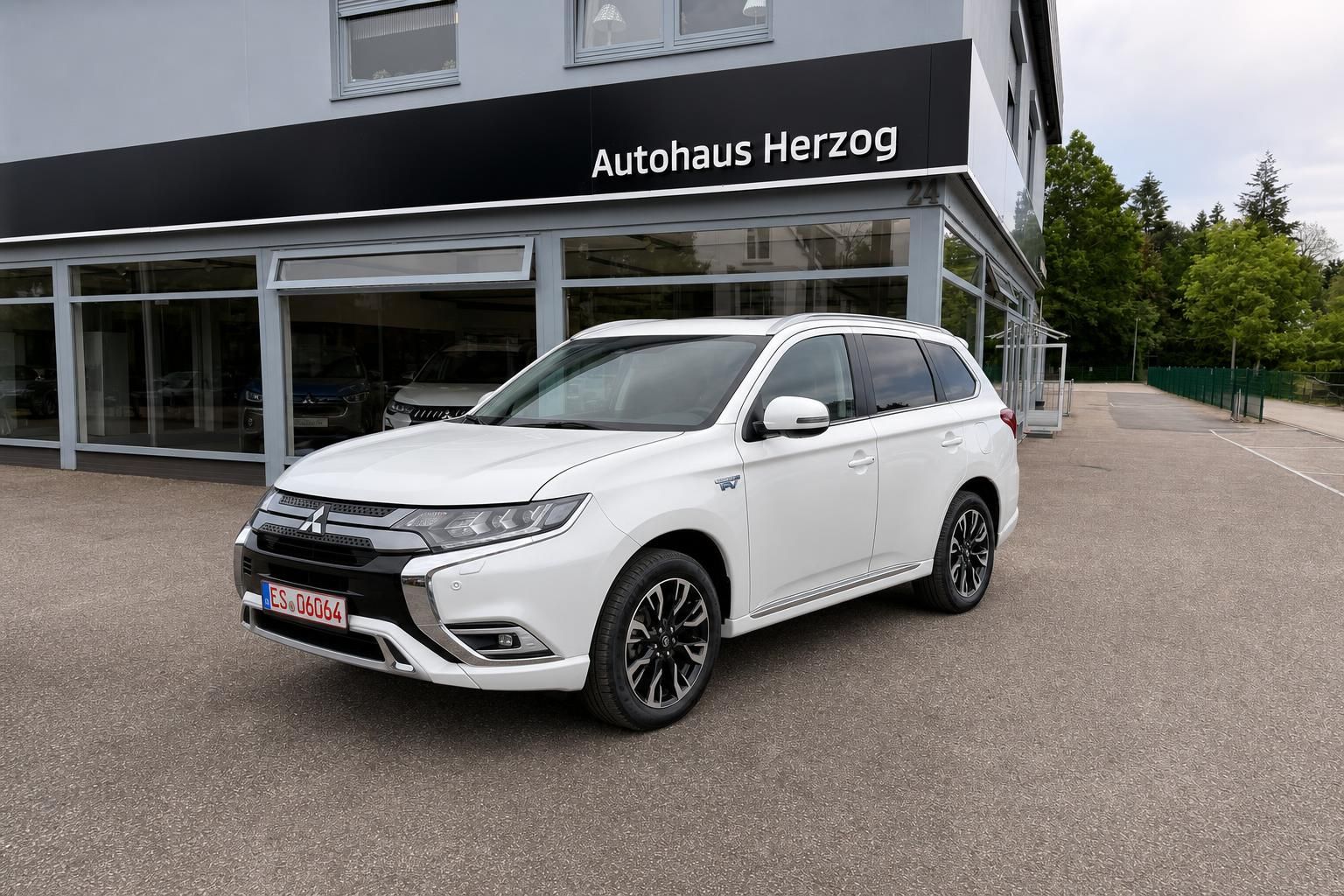 Mitsubishi Outlander PHEV in Weiß, Frontansicht vor Autohaus Herzog