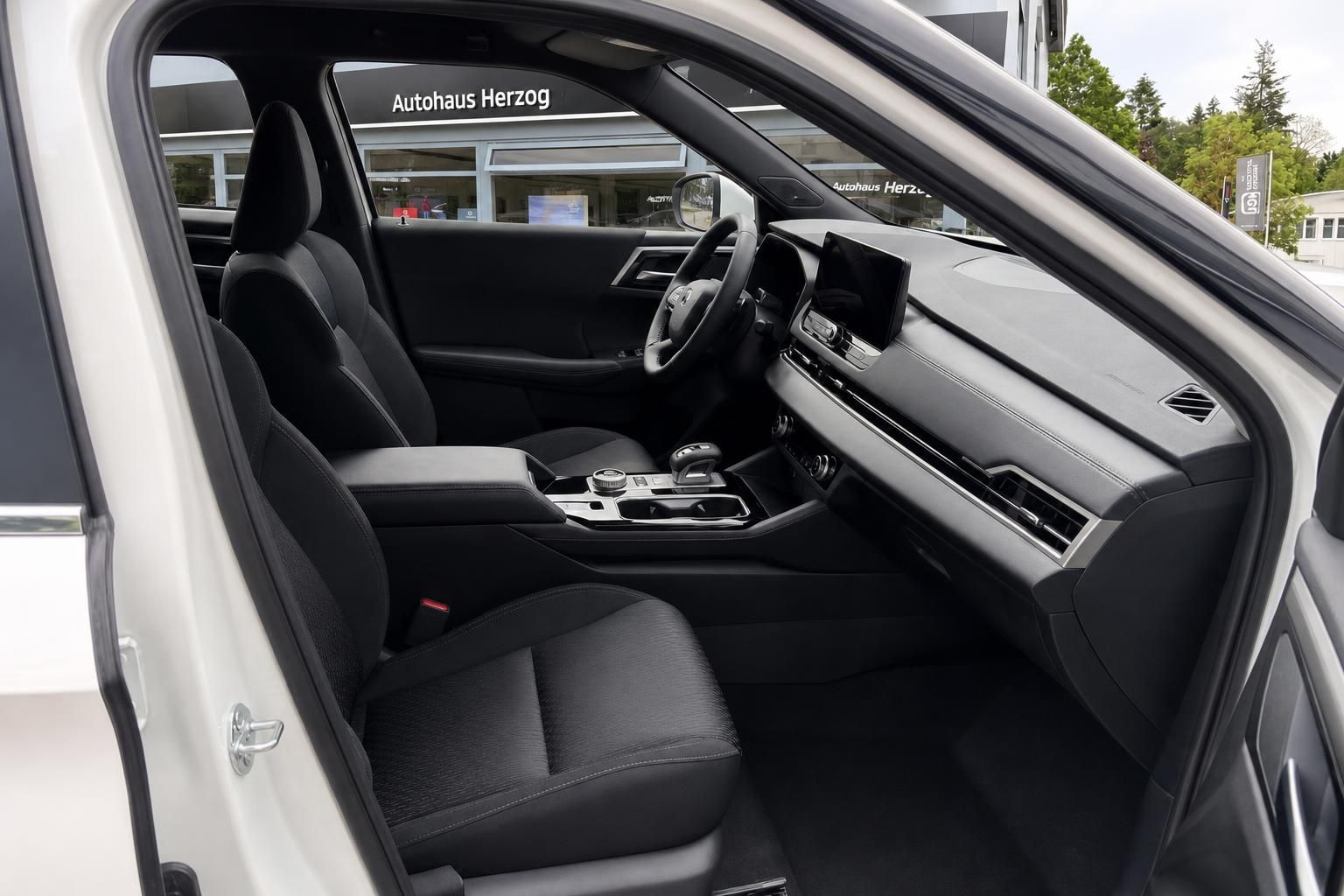 Innenraum eines weißen Mitsubishi mit Blick auf Vordersitze und Cockpit
