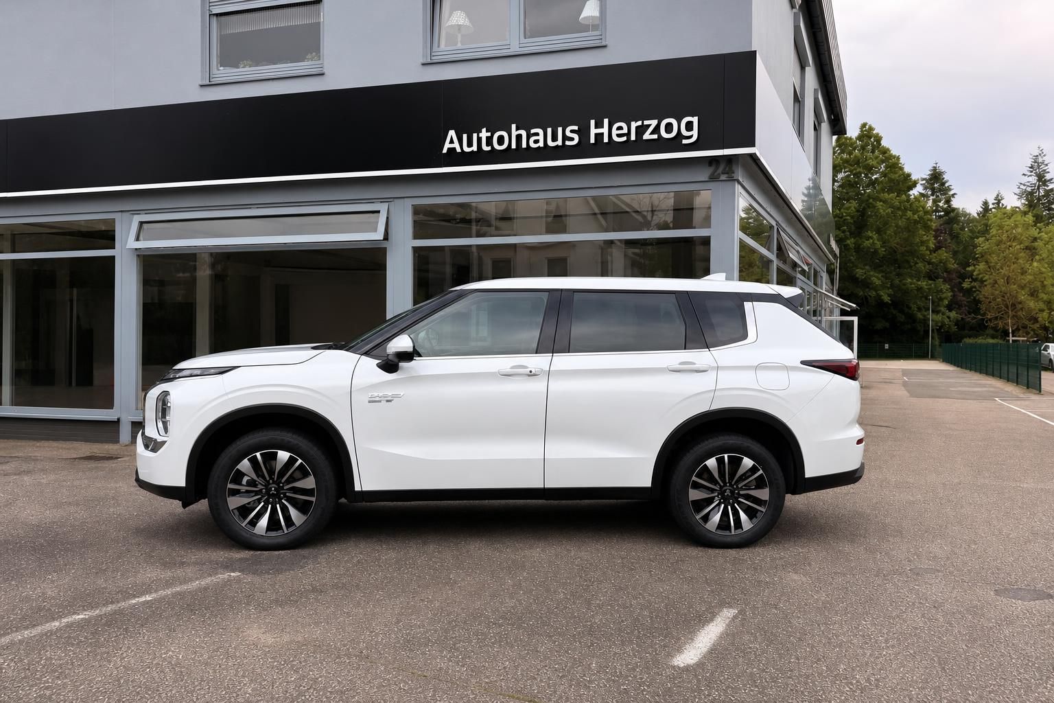 Mitsubishi Outlander weiß Seitenansicht vor Autohaus Herzog