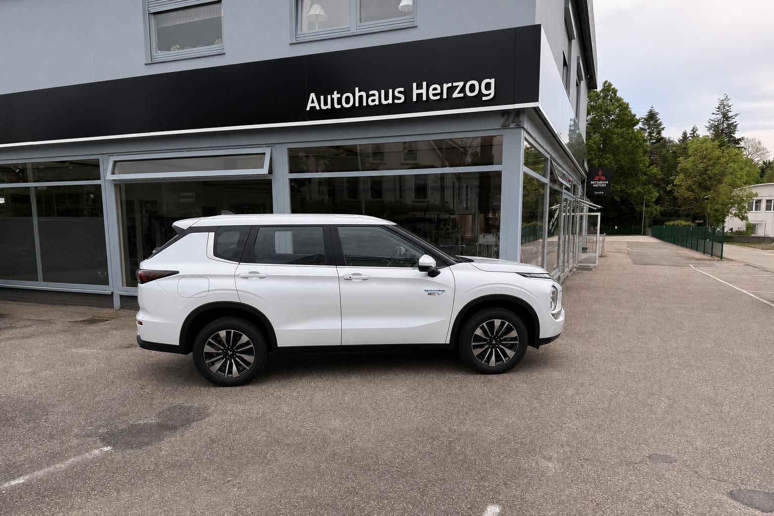 Mitsubishi Outlander PHEV weiß Seitenansicht vor Autohaus Herzog