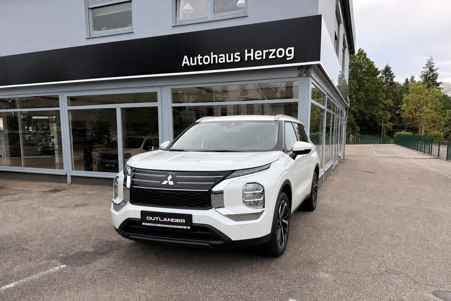 Mitsubishi Outlander weiß Frontansicht vor Autohaus Herzog