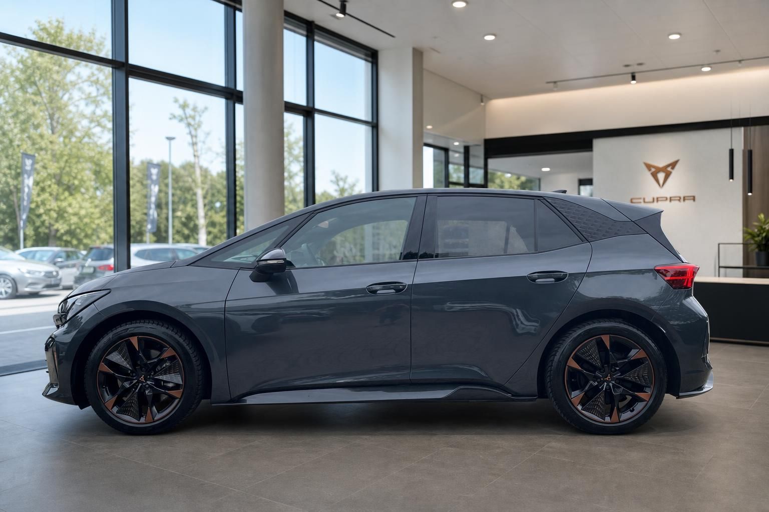 Cupra Born grau, Seitenansicht im Showroom vor Cupra-Logo