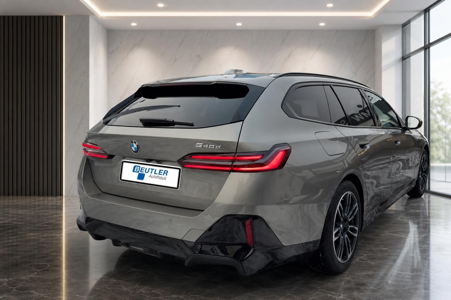 BMW 5er Touring 540d xDrive in Grau, Heckperspektive im Showroom