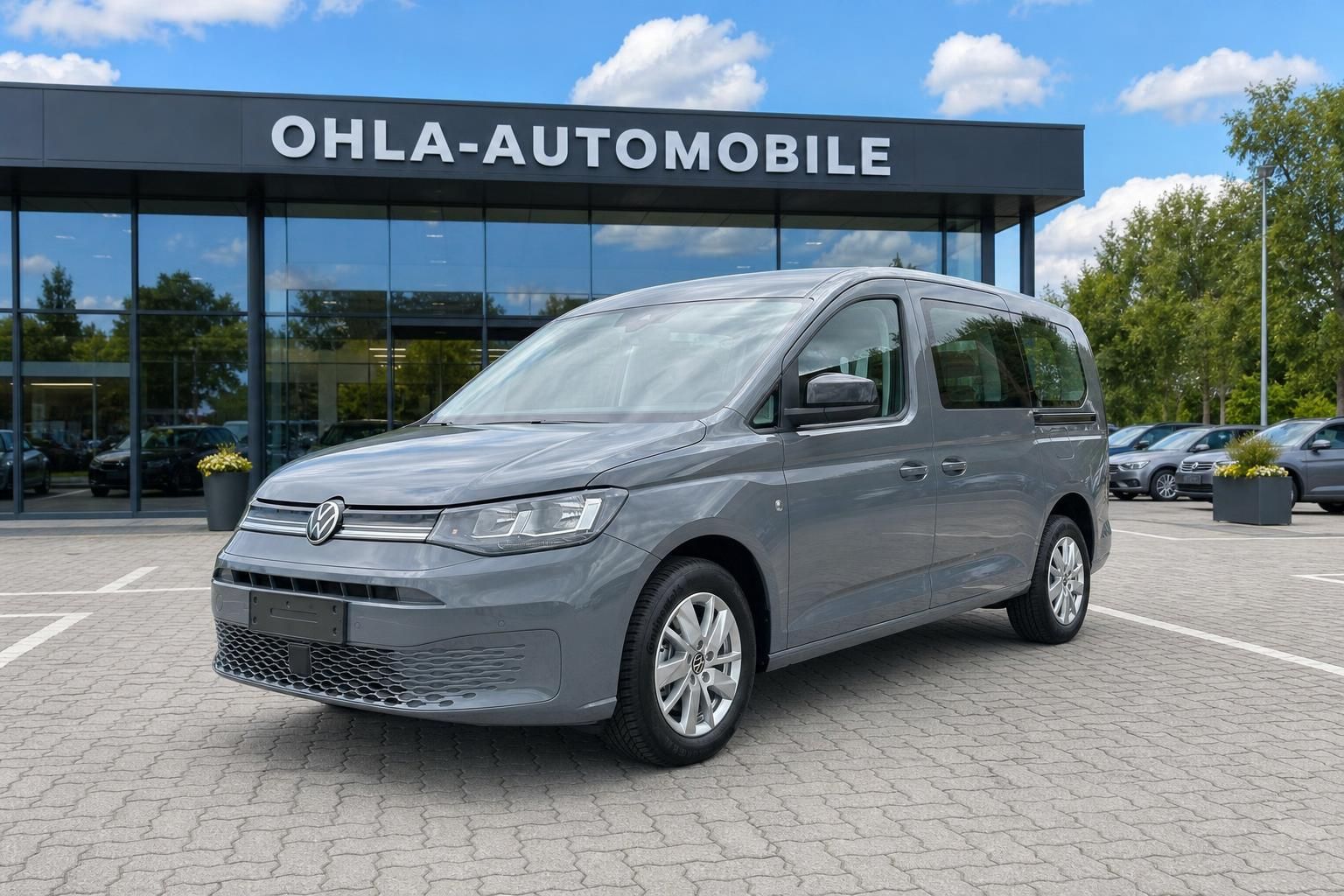 VW Caddy grau in Frontansicht auf Hof des Autohauses Ohla