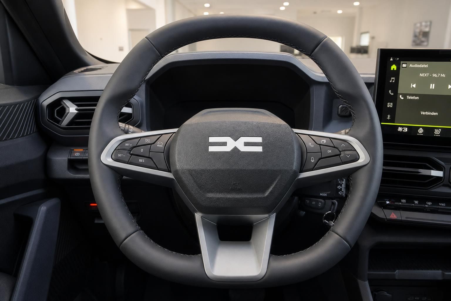 Lenkrad mit Multifunktionstasten und Digitalcockpit im Fahrzeuginnenraum