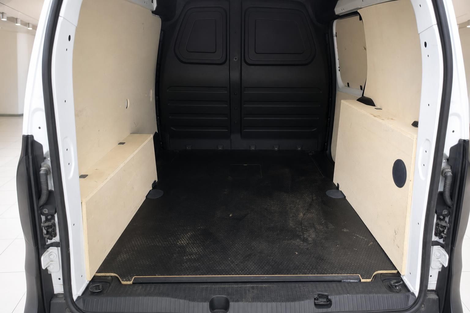 Laderaum eines weißen Transporters mit schwarzer Gummimatte und Holzverkleidung an den Seitenwänden