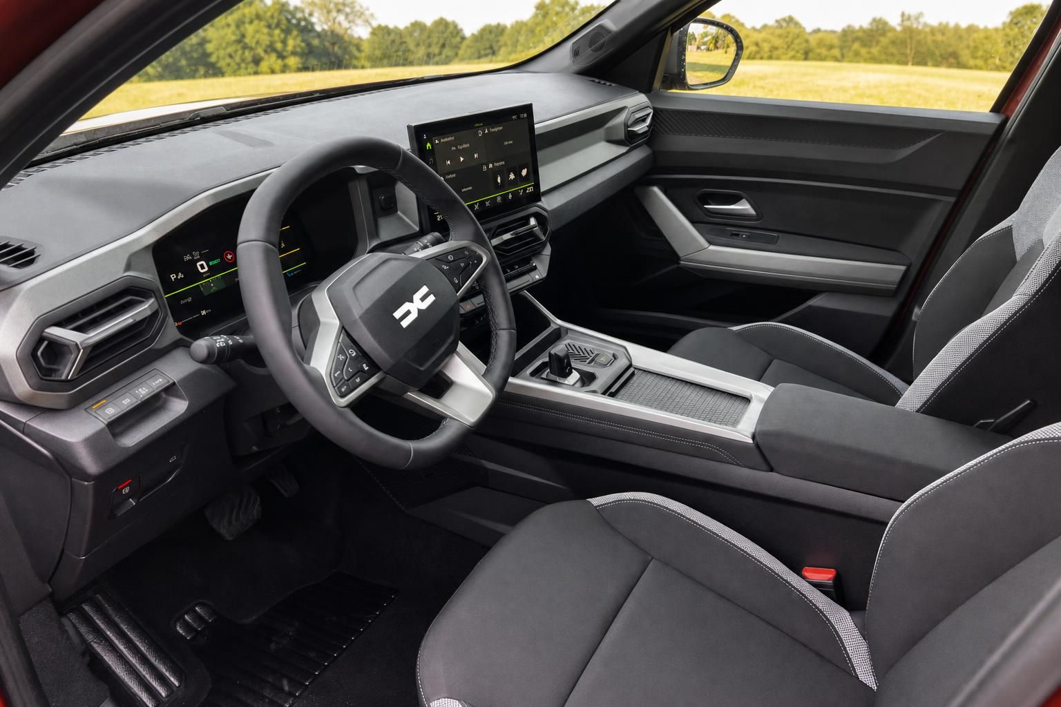Dacia Bigster Innenraum - Fahrersicht mit Lenkrad, Touchscreen und Landschaftsblick