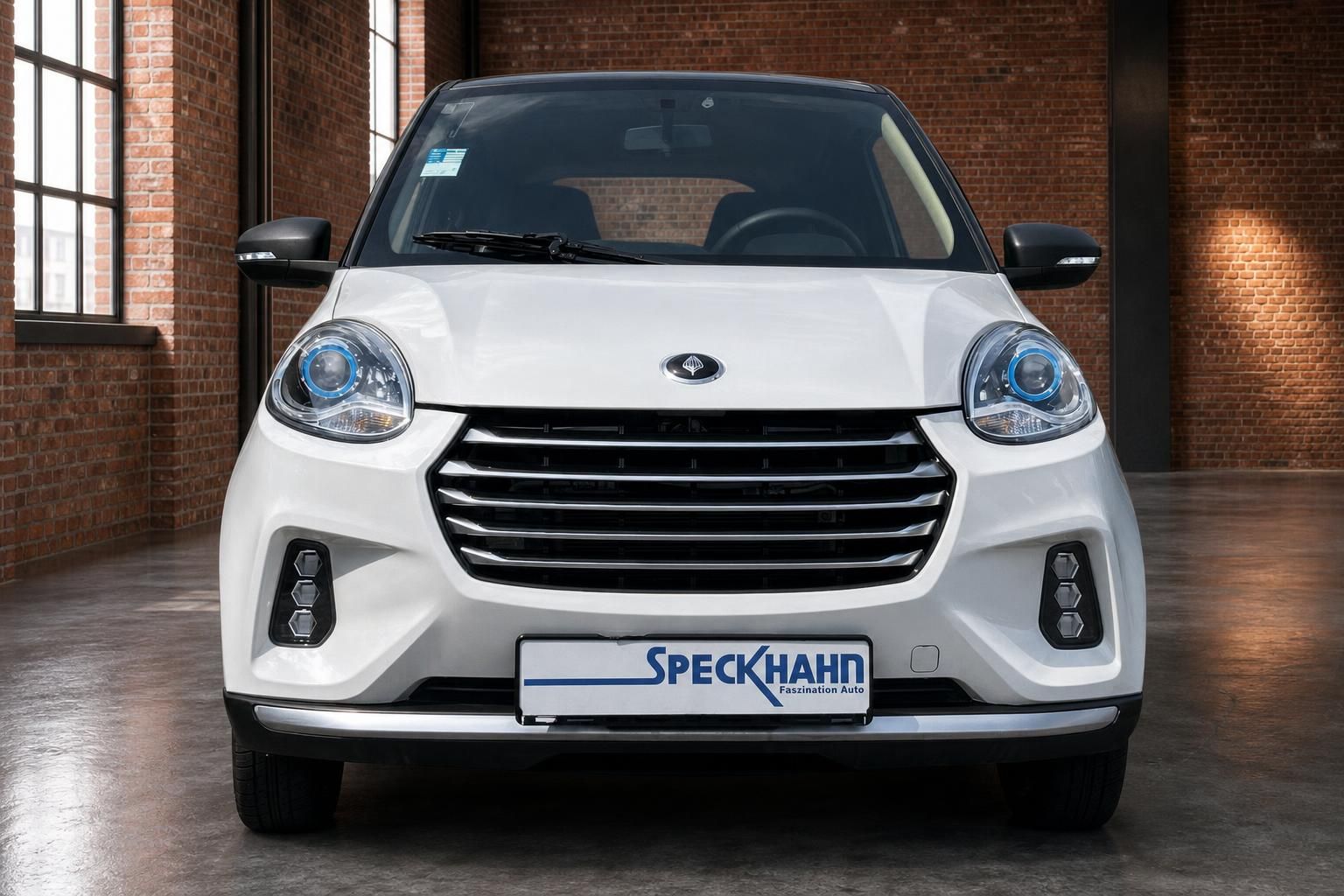 Weißes Elektroauto Frontansicht mit blauem LED-Tagfahrlicht und Speckhahn-Kennzeichenhalter