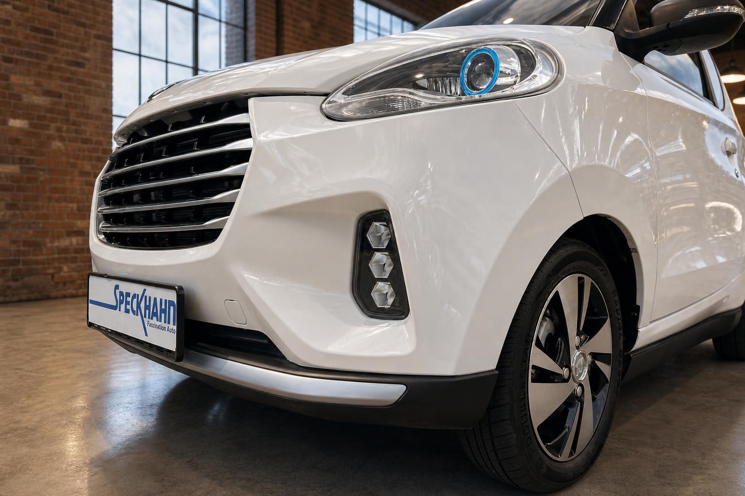 Weißes Elektroauto Frontdetail mit LED-Scheinwerfer, Kühlergrill und Leichtmetallfelge