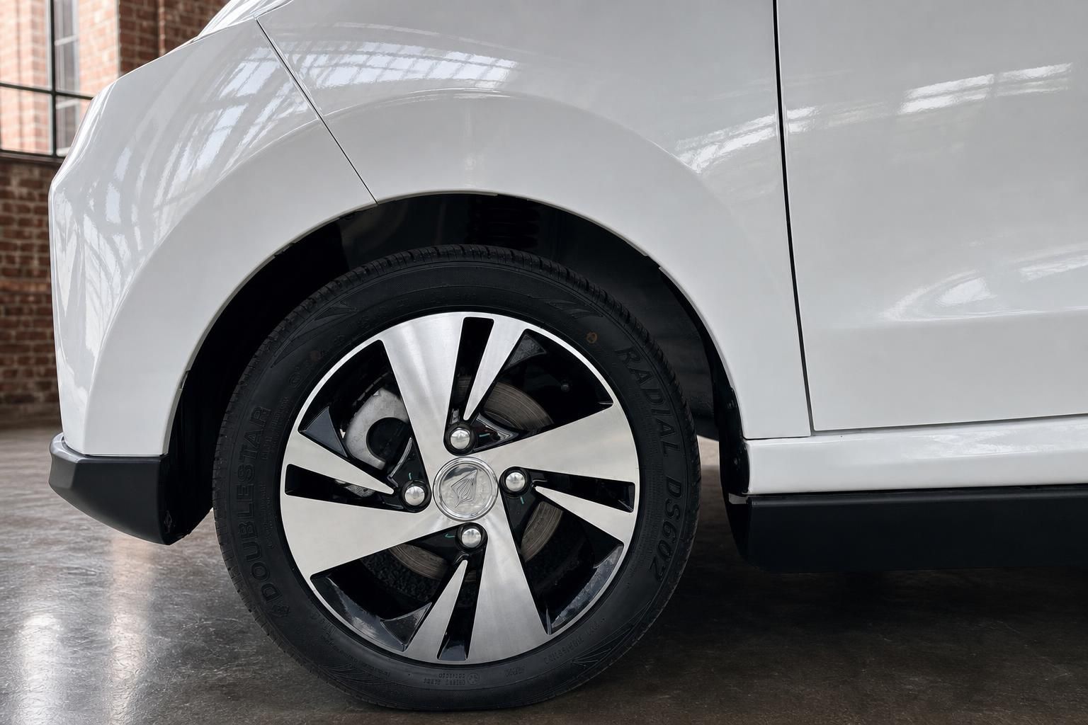Nahaufnahme Leichtmetallfelge weißes Elektroauto mit Doublestar-Reifen im Innenraum