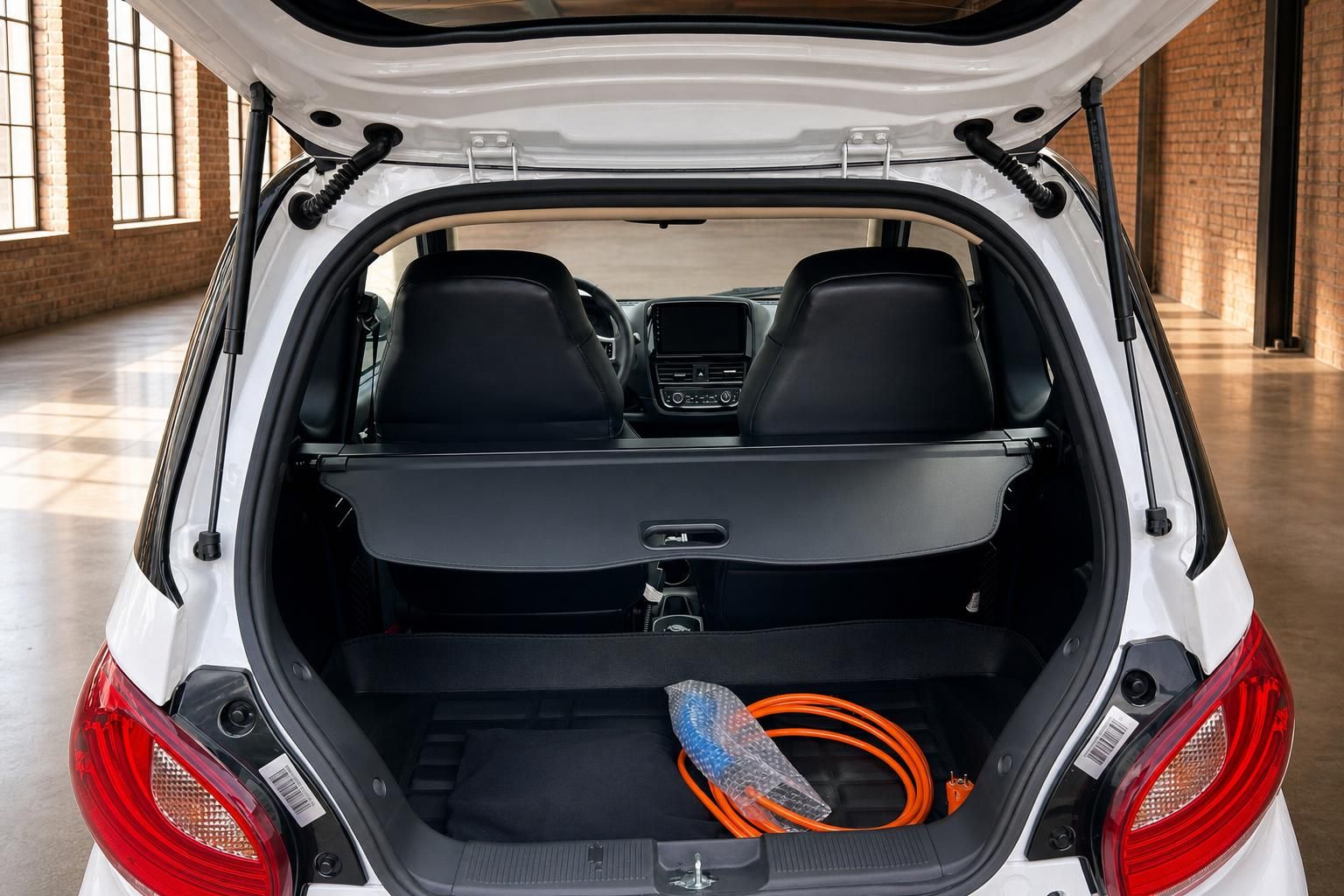 Kofferraum Elektroauto geöffnet mit Ladekabel in Orange und schwarzer Laderaumabdeckung