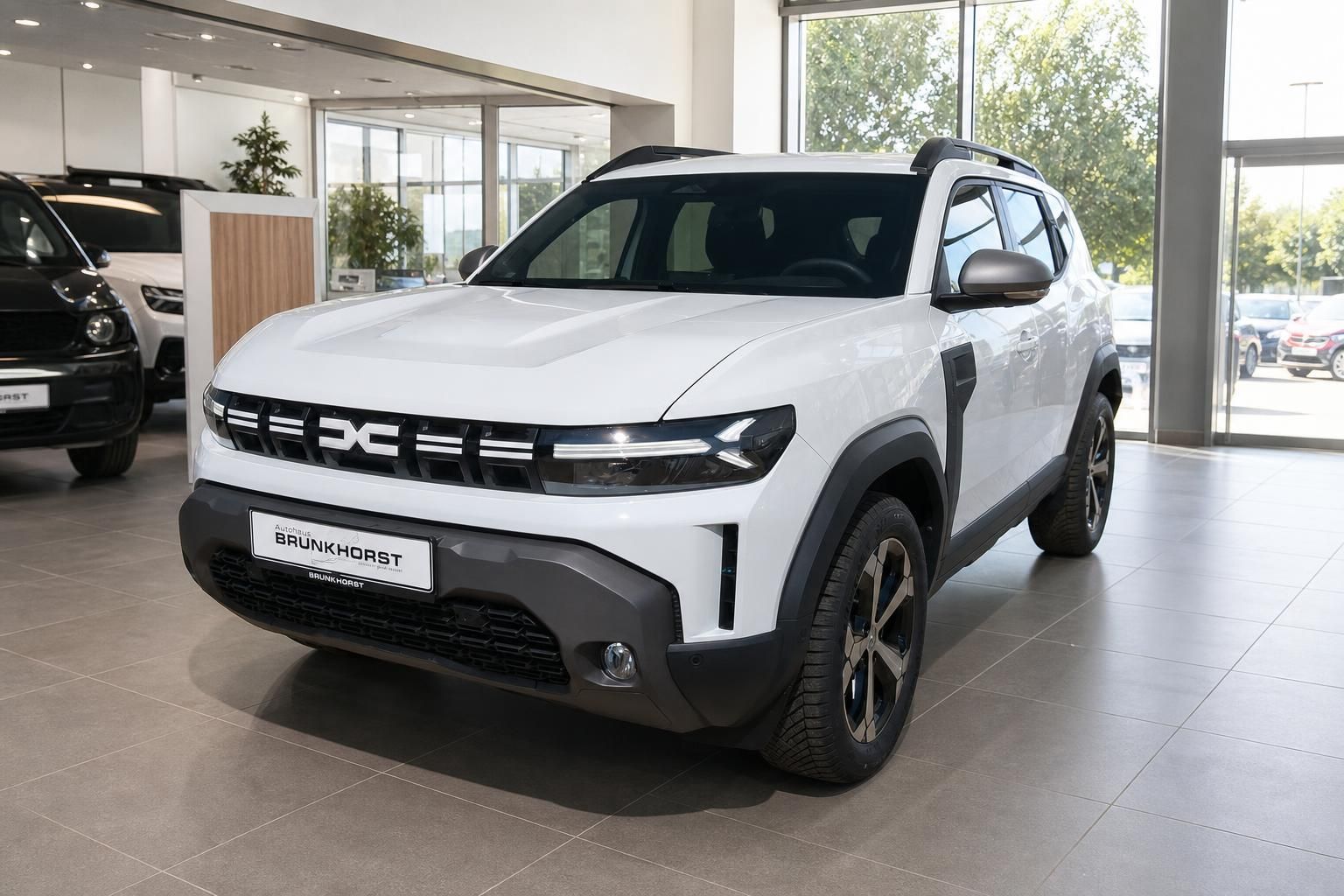 Weißer Dacia SUV im modernen Autohaus - Schrägsicht von vorne mit markanter Frontpartie