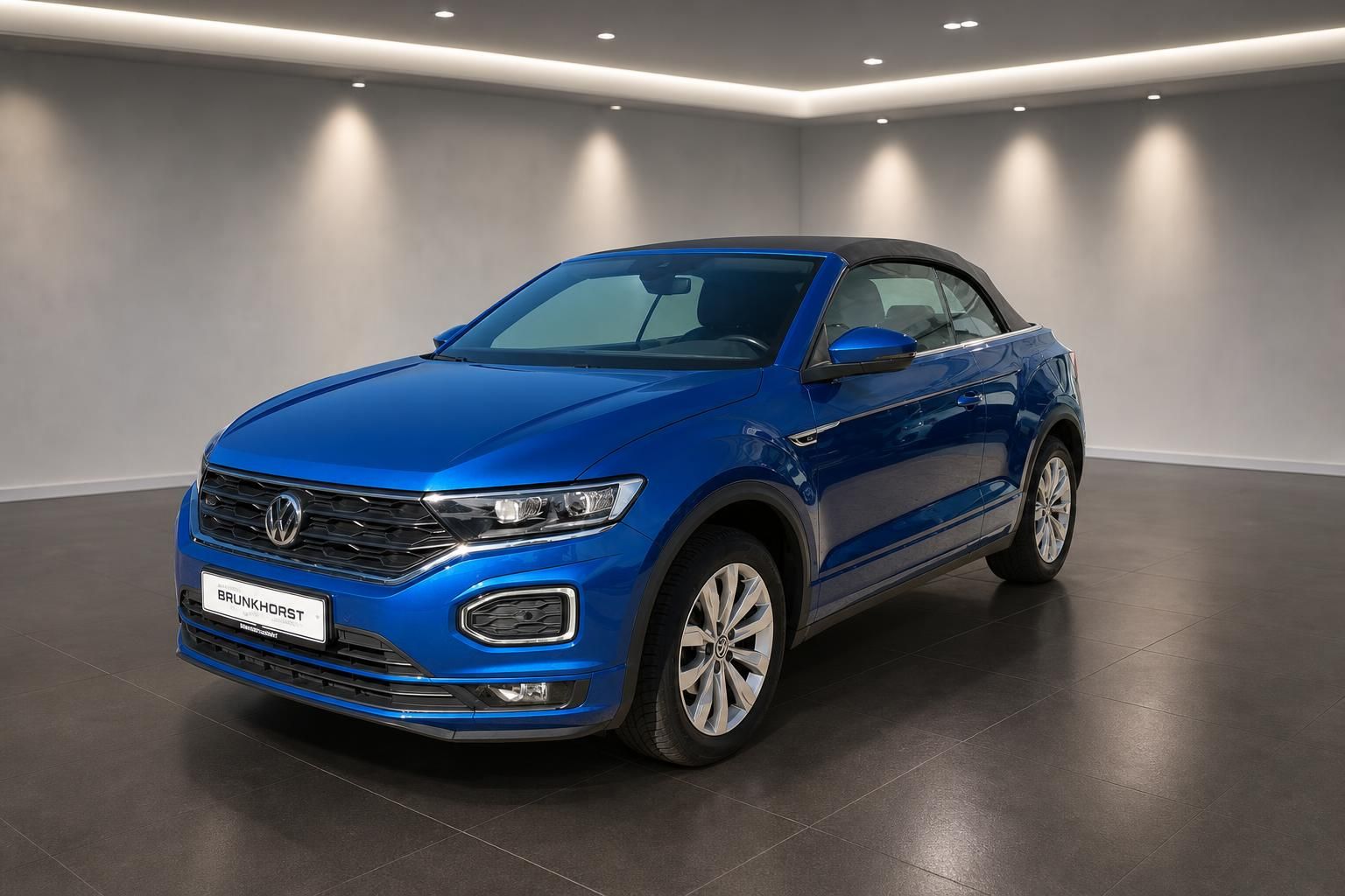 Blauer Volkswagen T-Roc Cabriolet Dreiviertelansicht vorne links im Autohaus Showroom