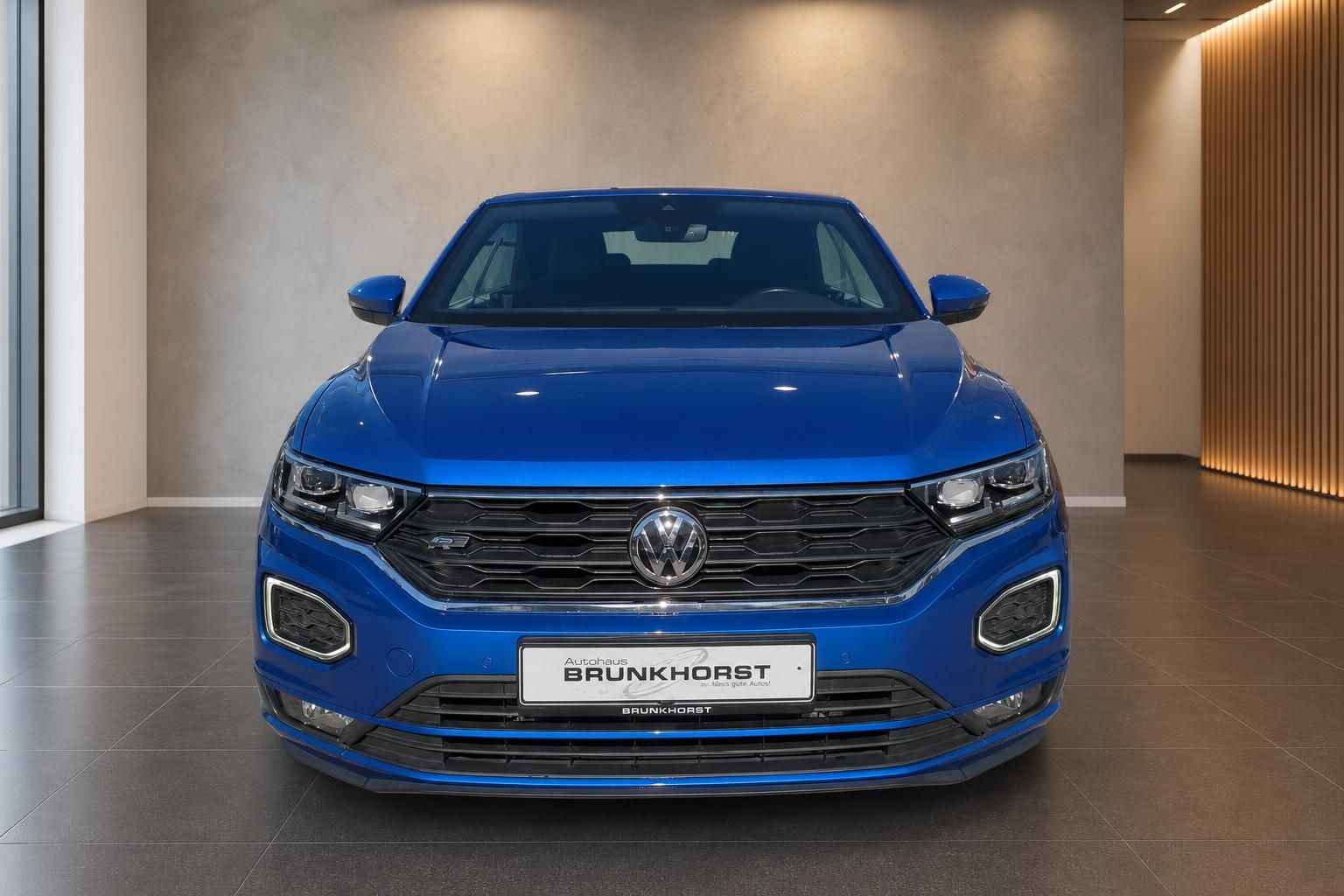 Volkswagen T-Roc Frontansicht blau mit charakteristischem VW-Kuehlergrill im Showroom