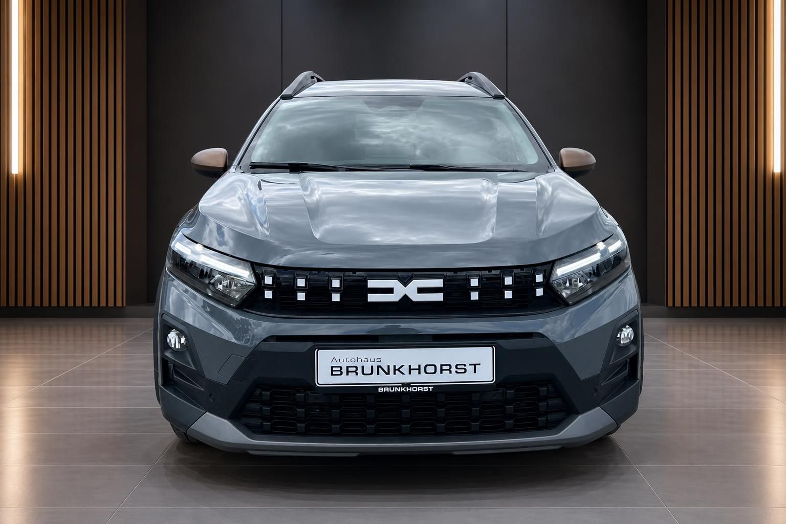 Dacia Jogger SUV grau Frontansicht - markanter Kühlergrill mit Dacia Logo im modernen Showroom