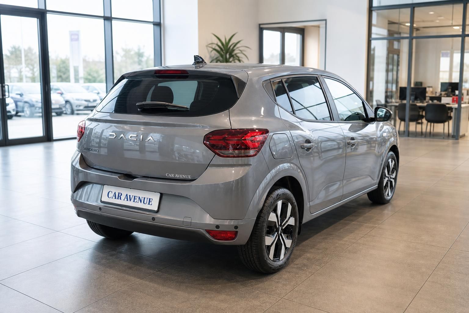 Dacia Sandero grau metallic Heckansicht schräg im Showroom mit Glasfront