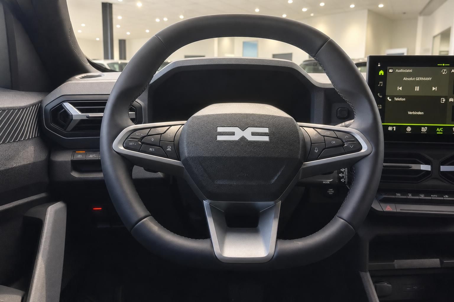 Dacia Lenkrad Nahaufnahme mit Logo und Infotainment-Display im Hintergrund