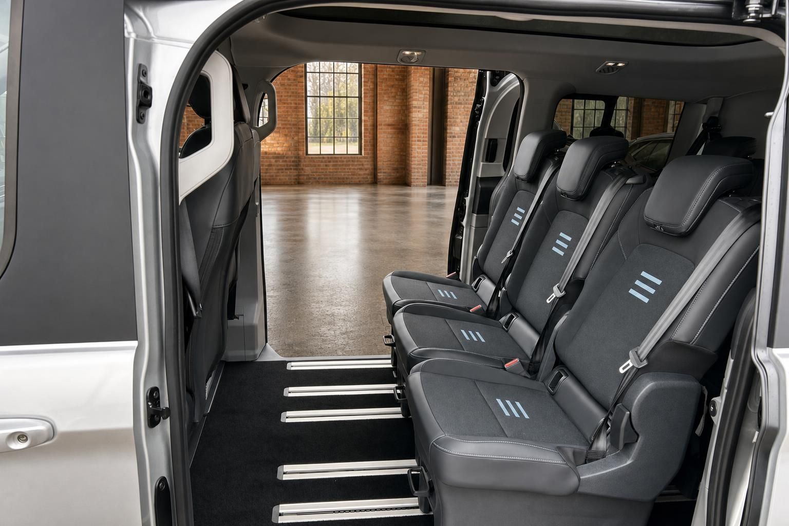 Ford Tourneo Custom Innenraum – geöffnete Schiebetür mit Einstiegsstufen und Sitzreihen