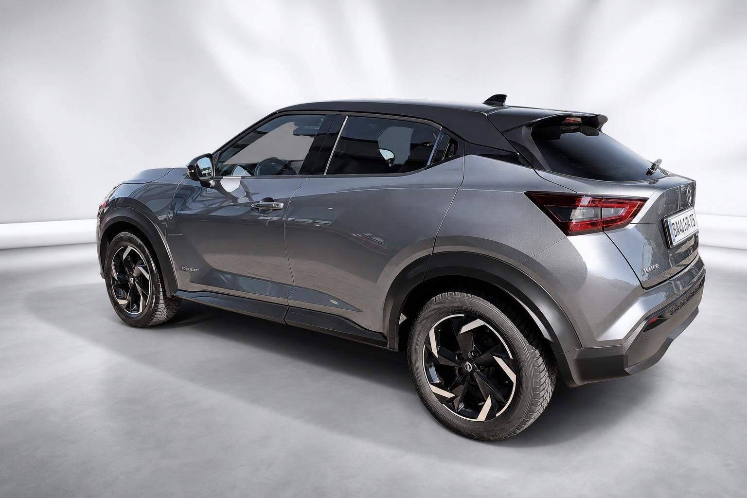 Nissan Juke Hybrid Heckansicht in Grau, schraeg von hinten