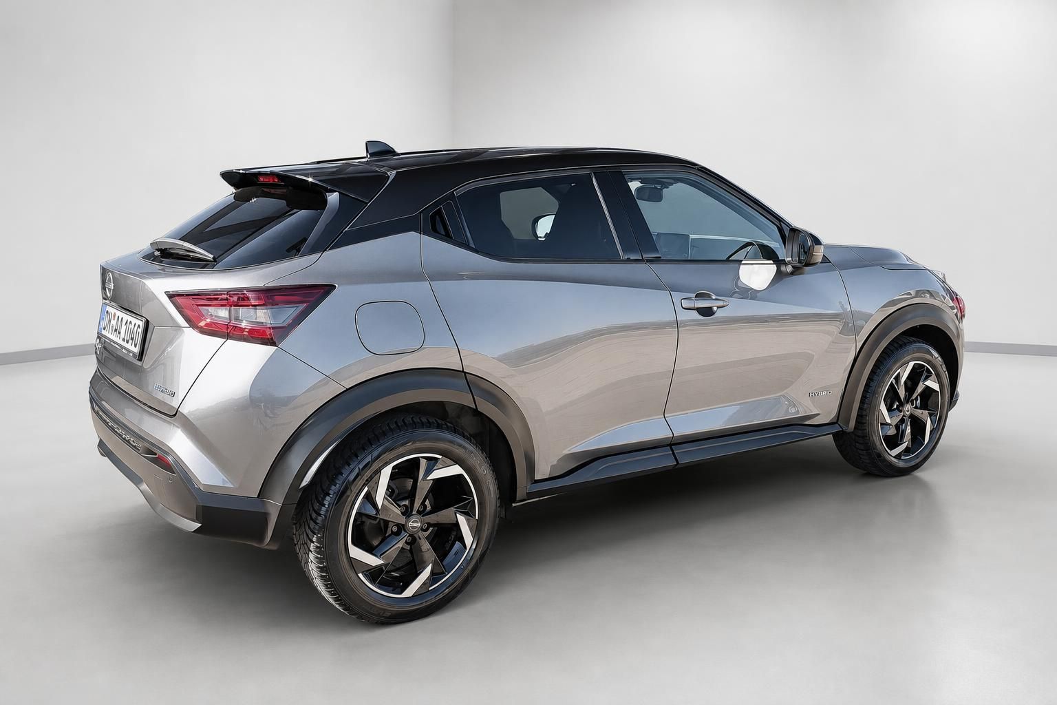 Nissan Juke Hybrid in Grau-Metallic, Heckansicht seitlich im Studio