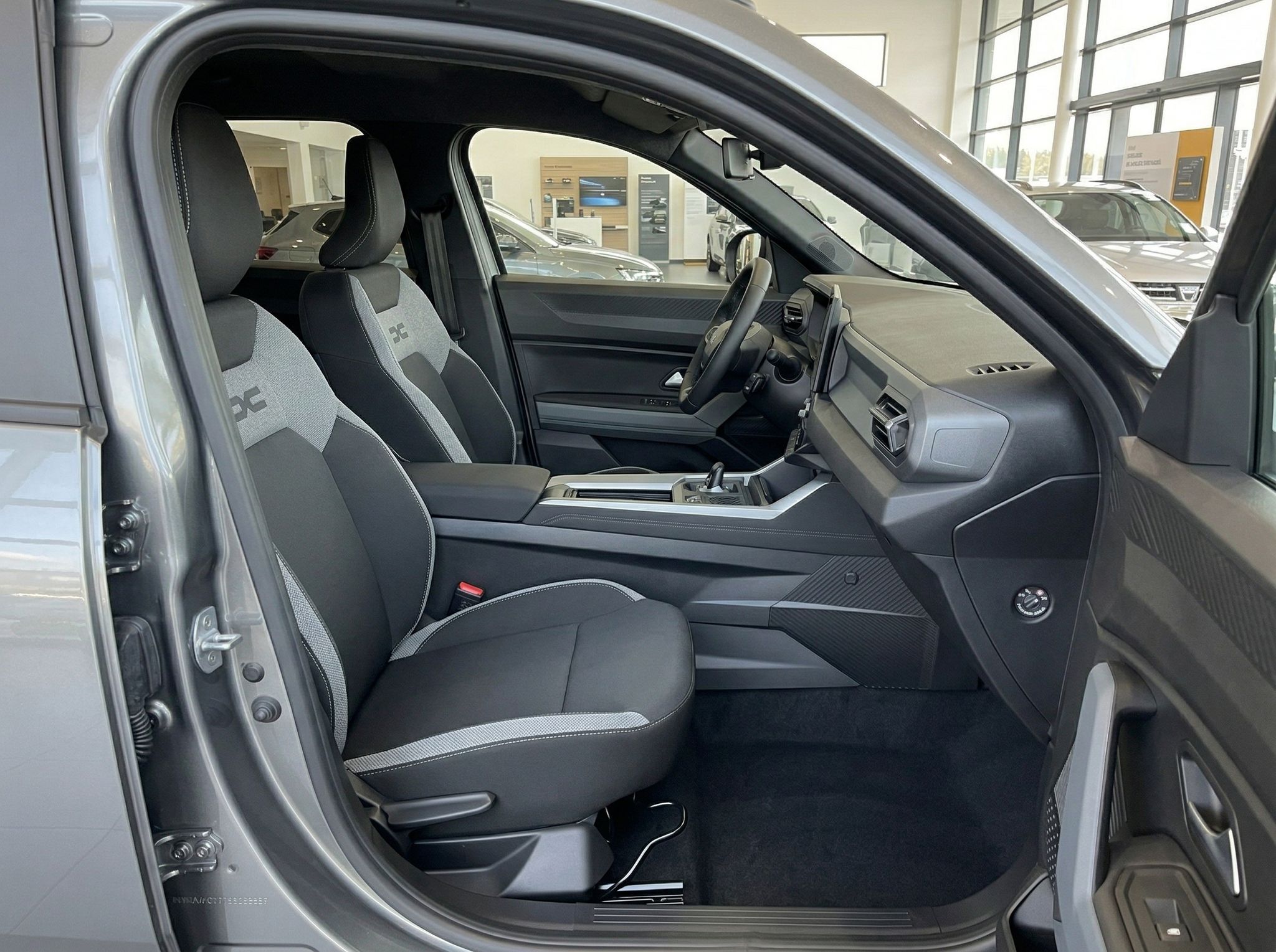 Fahrzeug-Innenraum mit grauen Sportsitzen und offener Beifahrertür