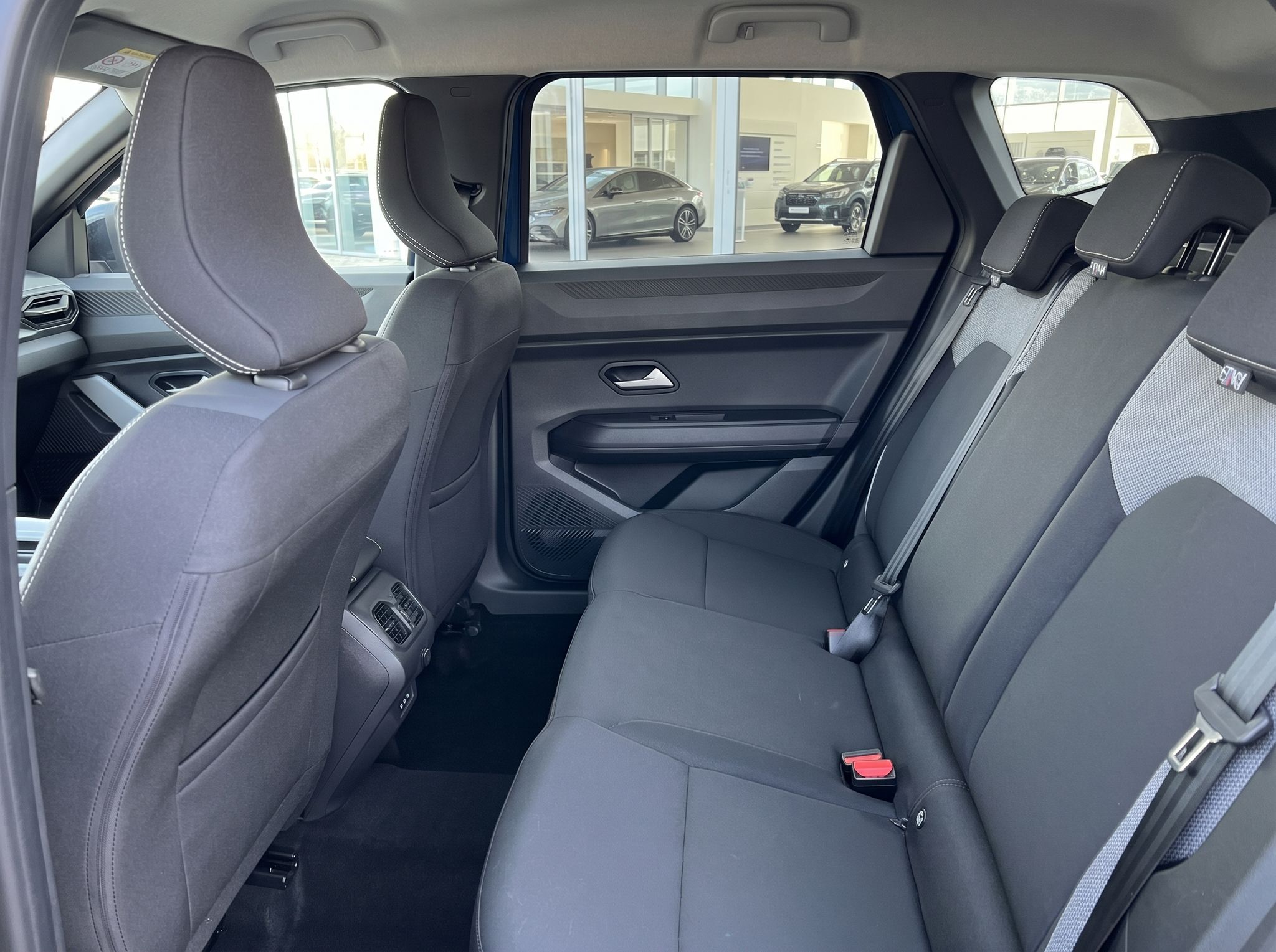 Rücksitzbank mit grauen Polstern und Sicherheitsgurten im modernen Fahrzeuginnenraum