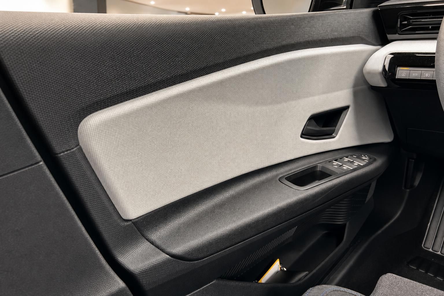 Fahrzeugtürverkleidung mit grau-weißen Materialien und Fensterheberschaltern