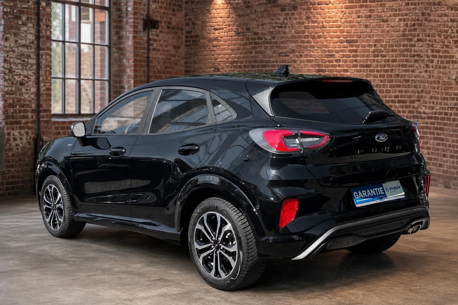 Ford Puma schwarz Heckansicht schraeg im Industrie-Ambiente