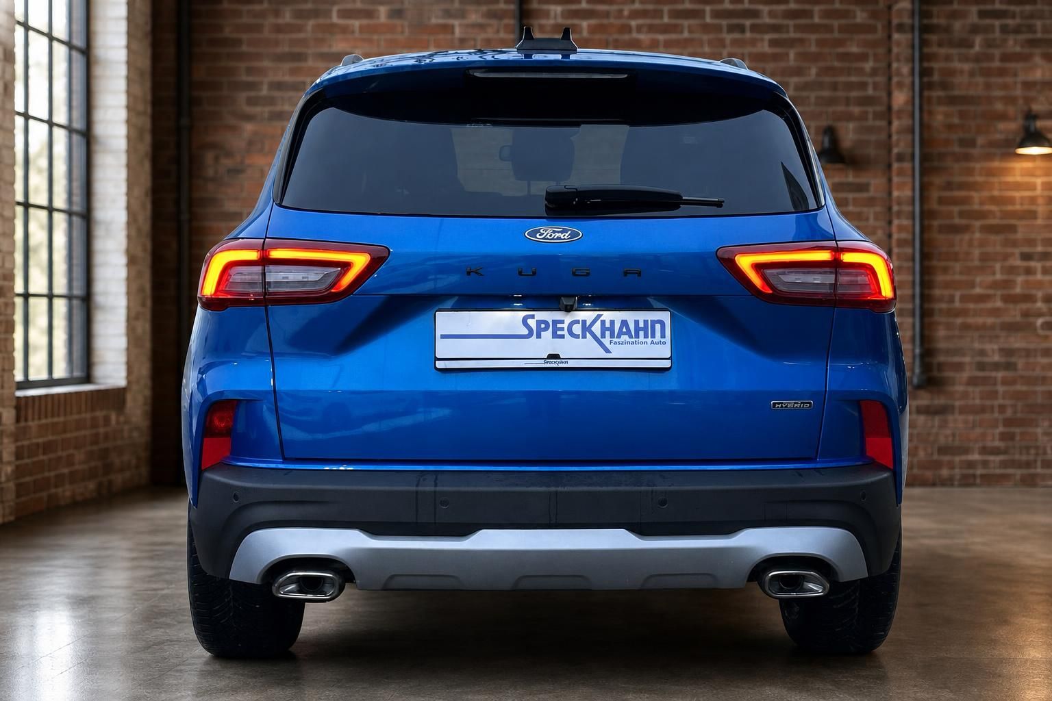 Ford Kuga Hybrid blau Heckansicht in Halle mit Backsteinwand
