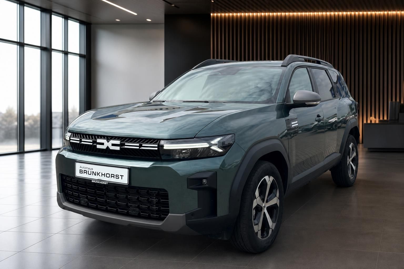 Dacia SUV grün metallic Frontansicht im modernen Autohaus Showroom