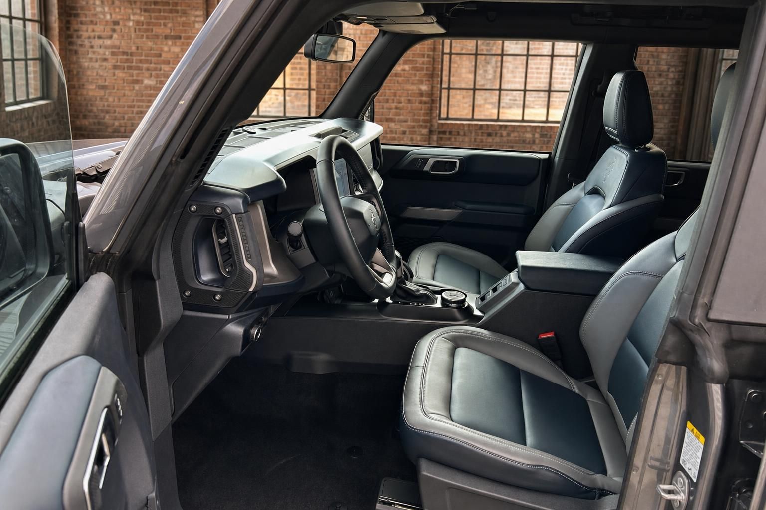 Ford Bronco Innenraum mit Lenkrad, Ledersitzen und Mittelkonsole – Fahrerseite geöffnet