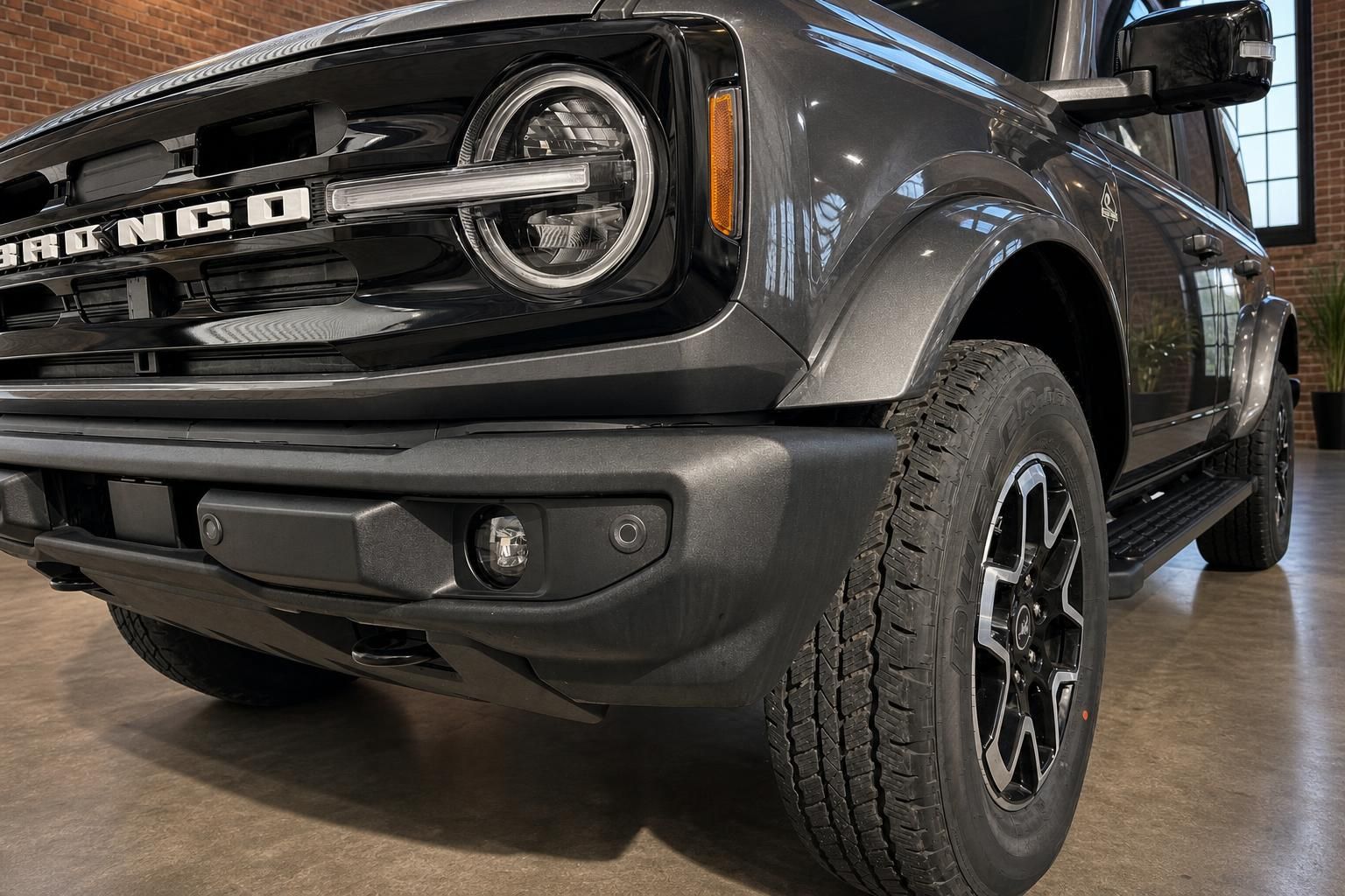 Ford Bronco Detailaufnahme Front links mit Scheinwerfer, Grill und Bronco-Schriftzug in Braun